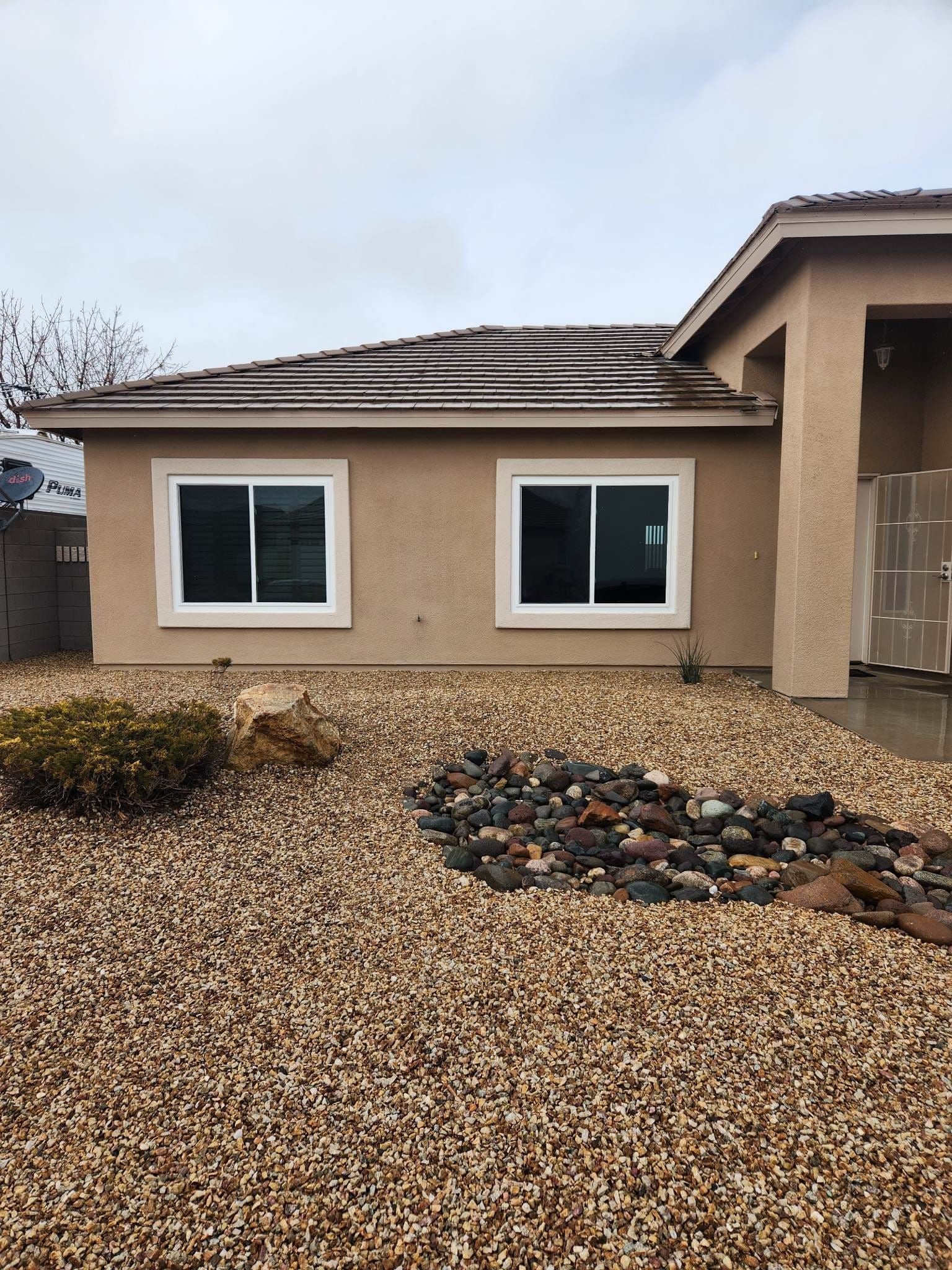 A house with a lot of windows and gravel in front of it.