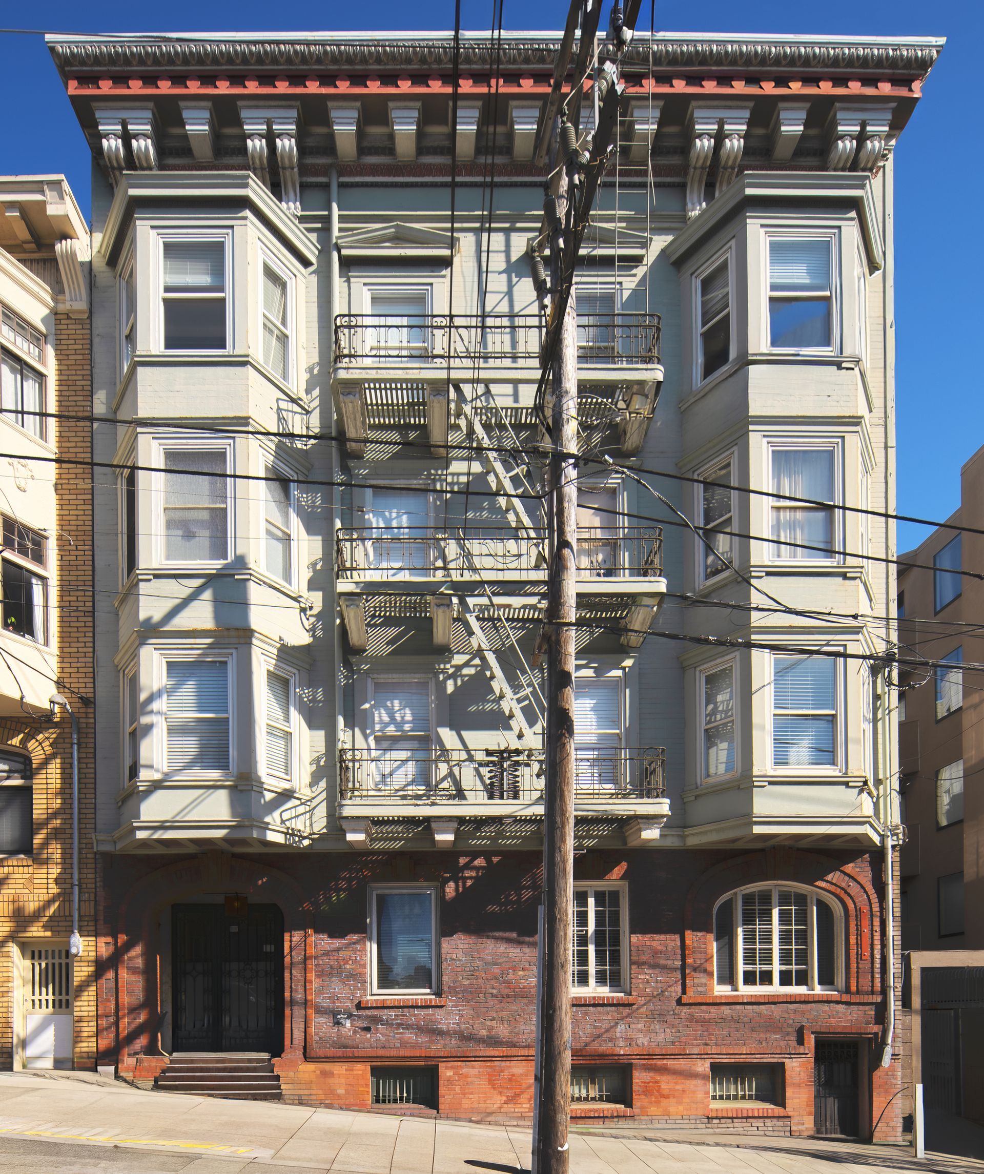 Multi-story brick building with green trim, arched doorway, and balcony.