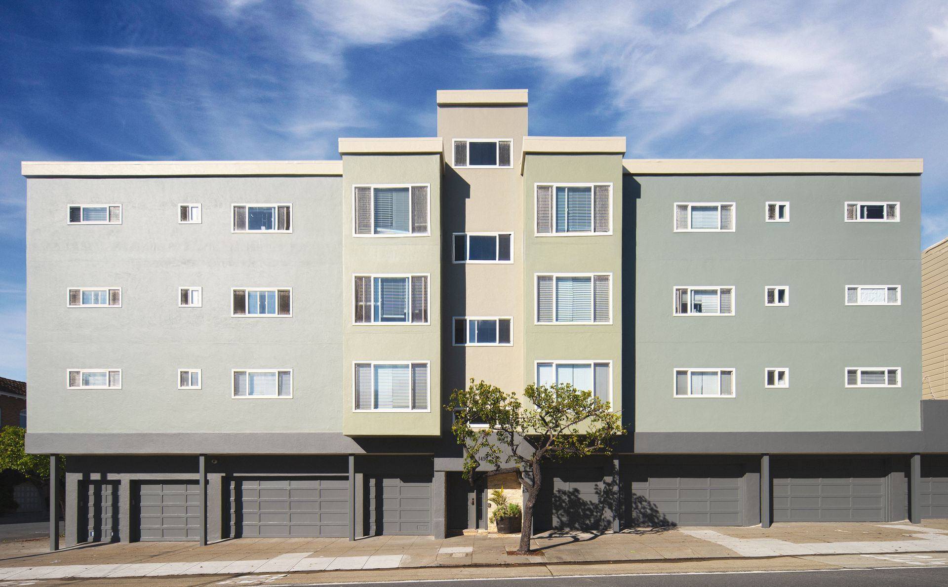 Multi-story light gray building with small windows; fire escape on the side.