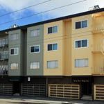 Multi-story apartment building with garage doors, in shades of gray and yellow.