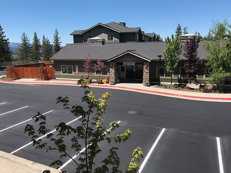 A one-story building with a parking lot in front. The building has a stone facade and dark roof.