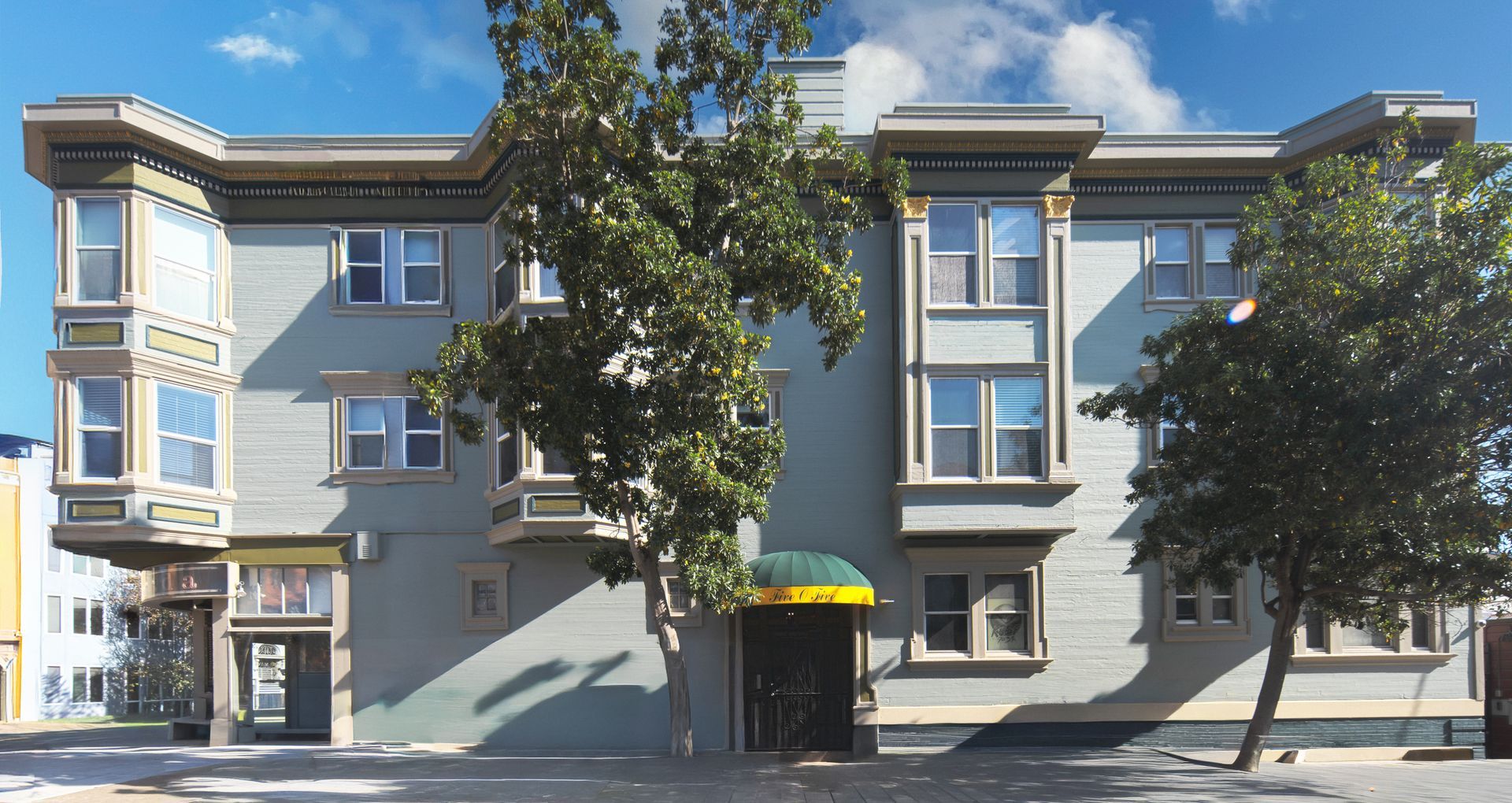 Red brick apartment building with bay windows; cars parked out front.