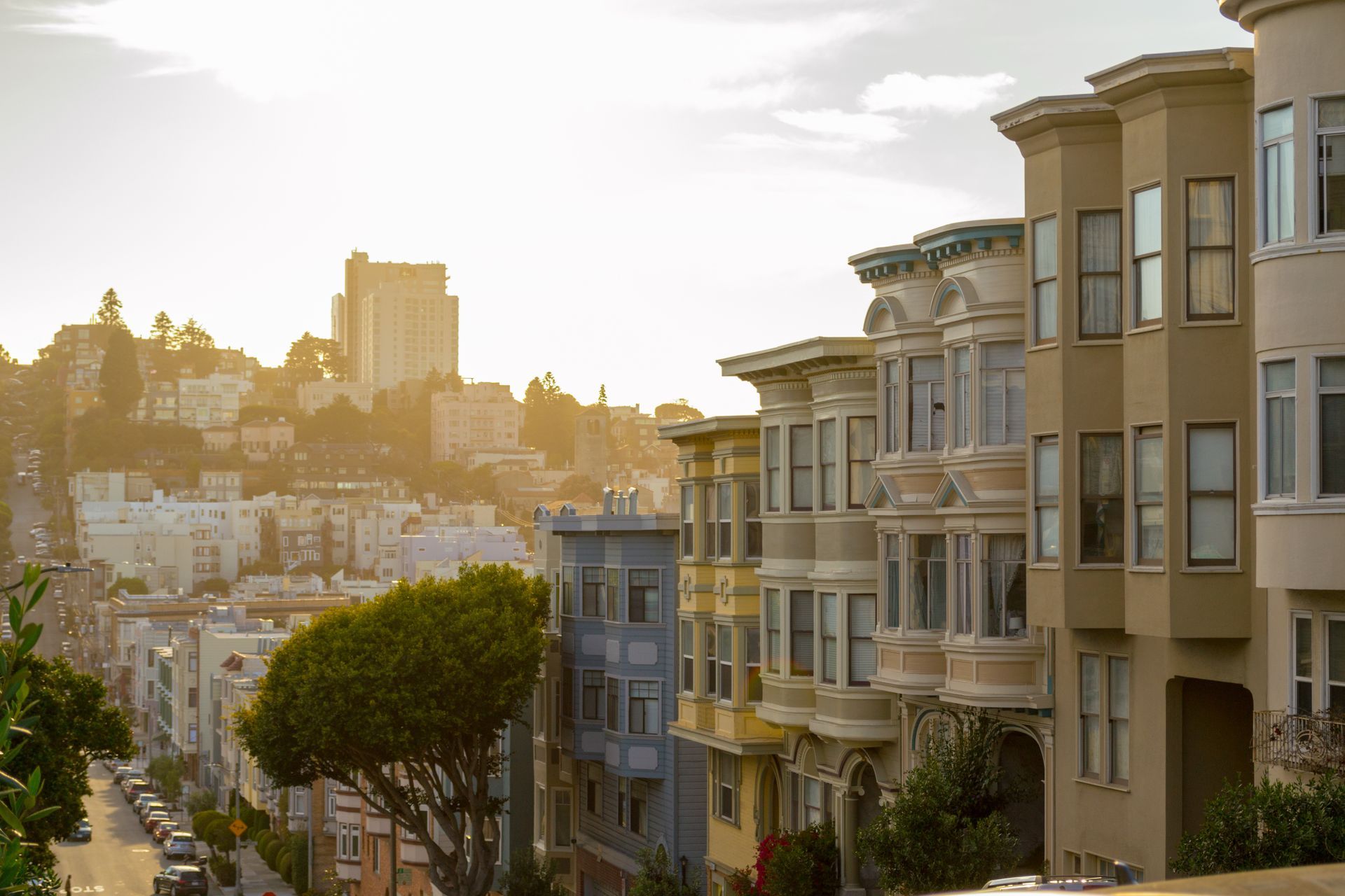 Row houses on a San Francisco hill, illuminated by sunlight.