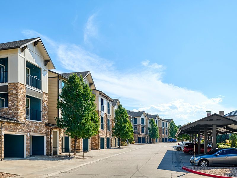 Multi-story beige apartment building on a street corner with a clear sky and power lines.