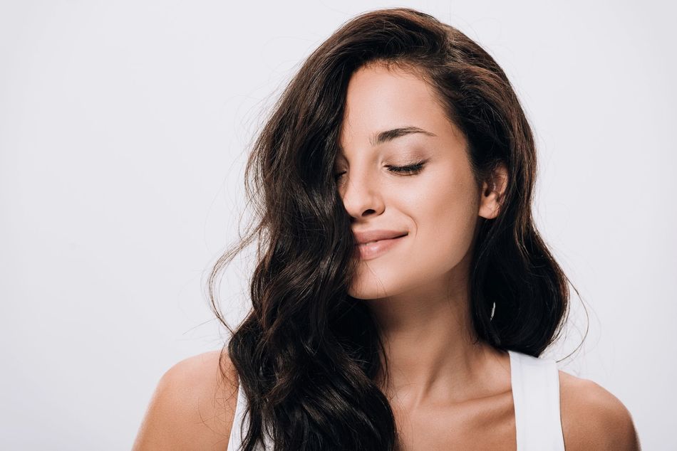 Donna sorridente con lunghi capelli scuri su sfondo chiaro