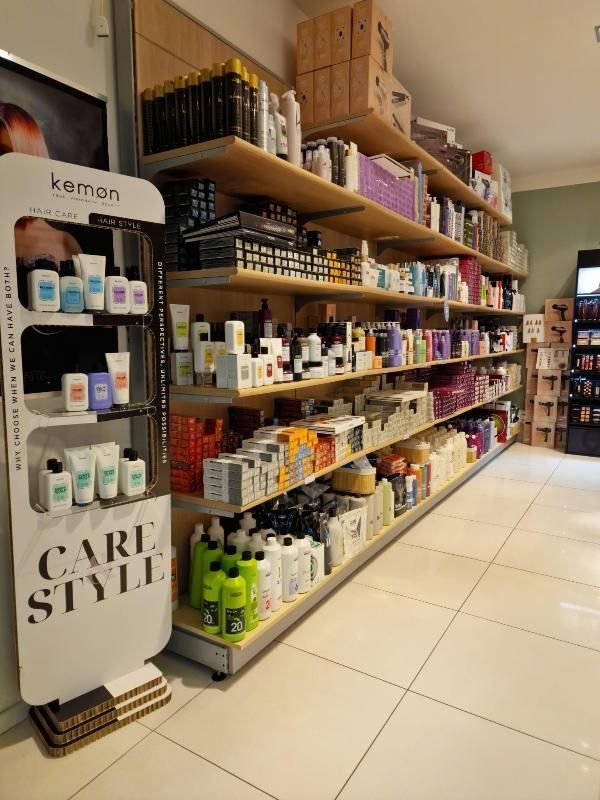 Scaffali di prodotti per la cura dei capelli in una corsia di un negozio, con un espositore Kemon in primo piano.