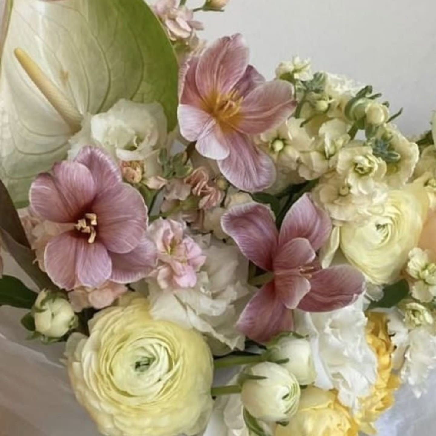 Bouquet di fiori rosa e gialli, tra cui tulipani, ranuncoli e anthurium.