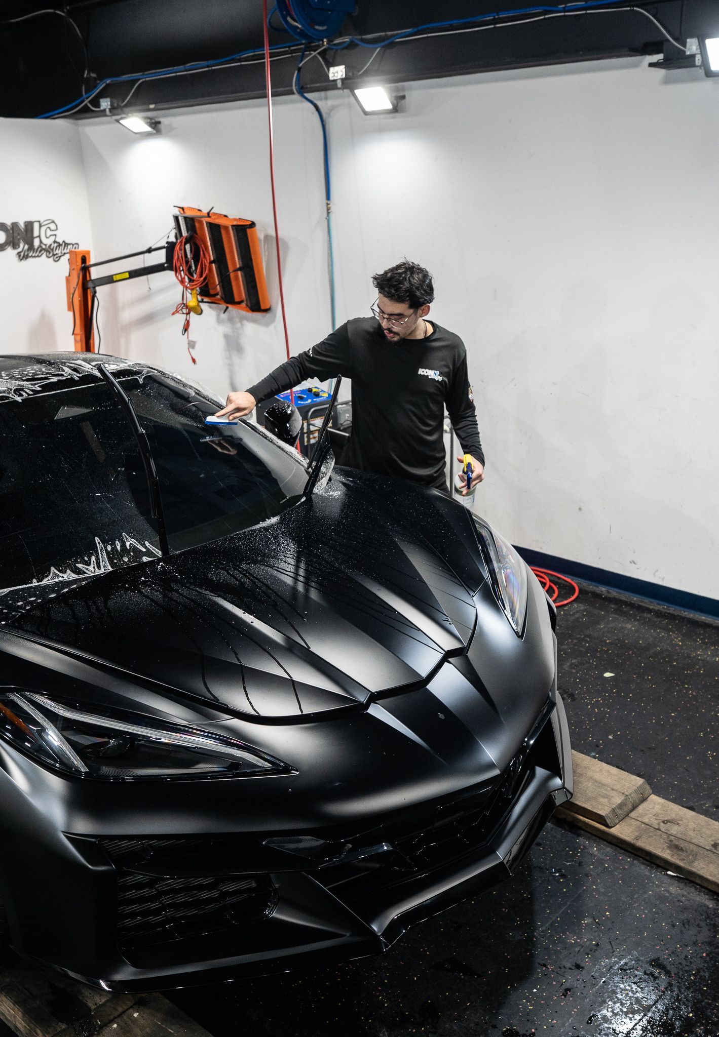 A person installing window tint on a black car windshield with a squeegee.