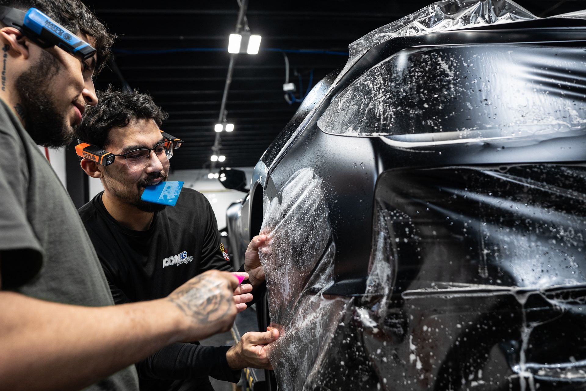 Person using a heat gun and squeegee to apply film to a car side mirror.
