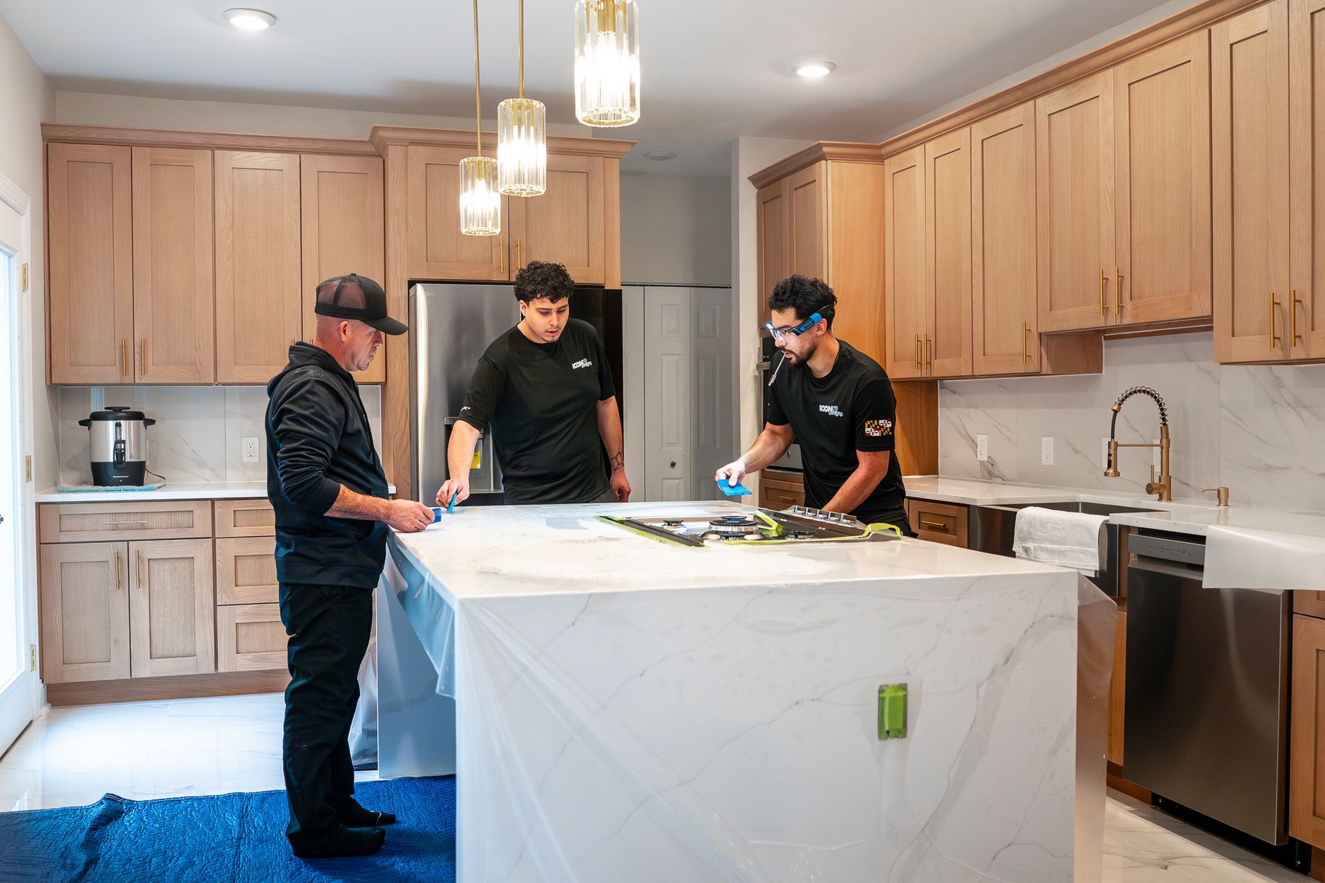 Modern white kitchen with stainless steel appliances, marble countertops, and wooden floors.