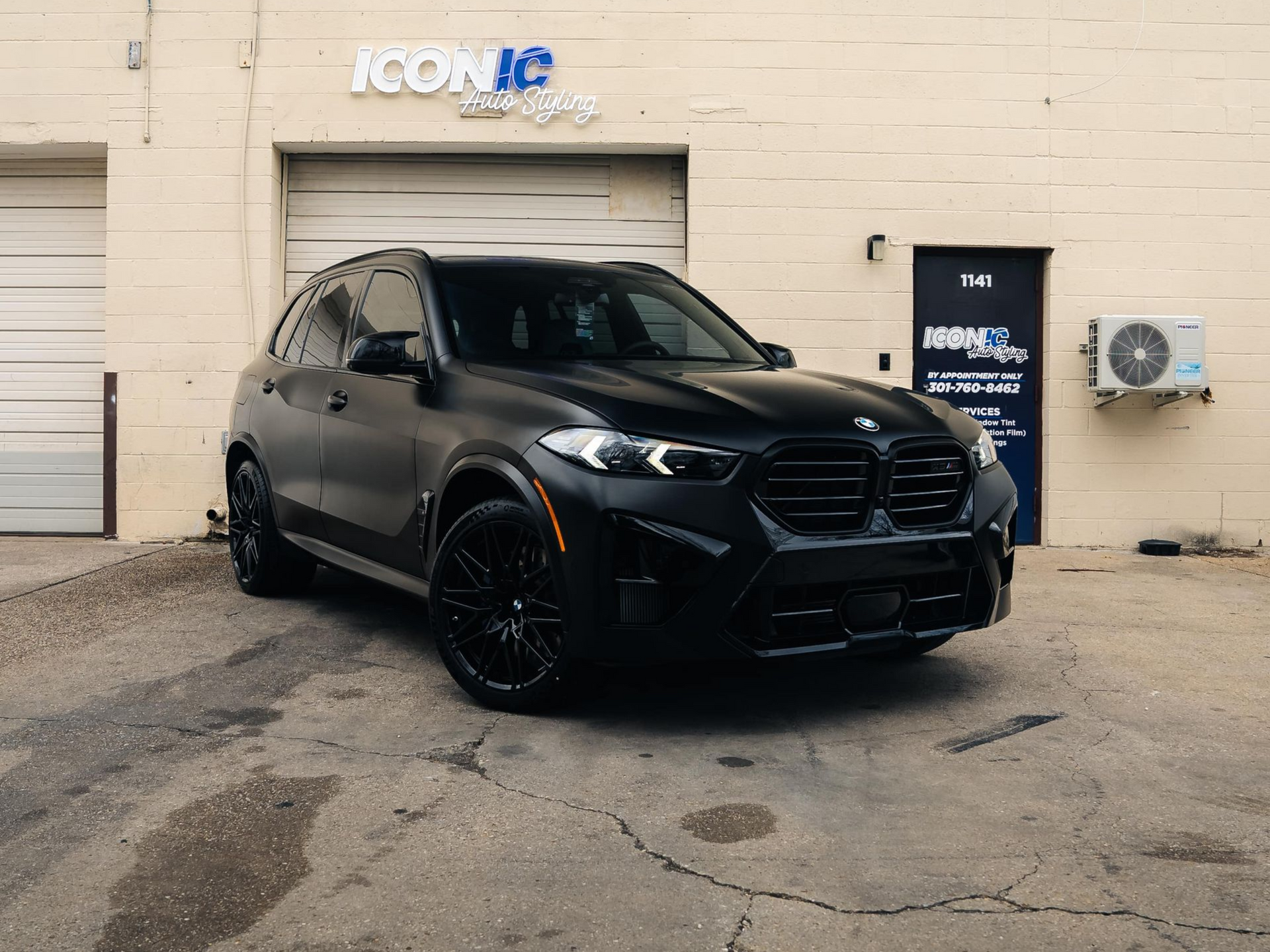 Black BMW SUV parked in front of a building with a closed garage door.