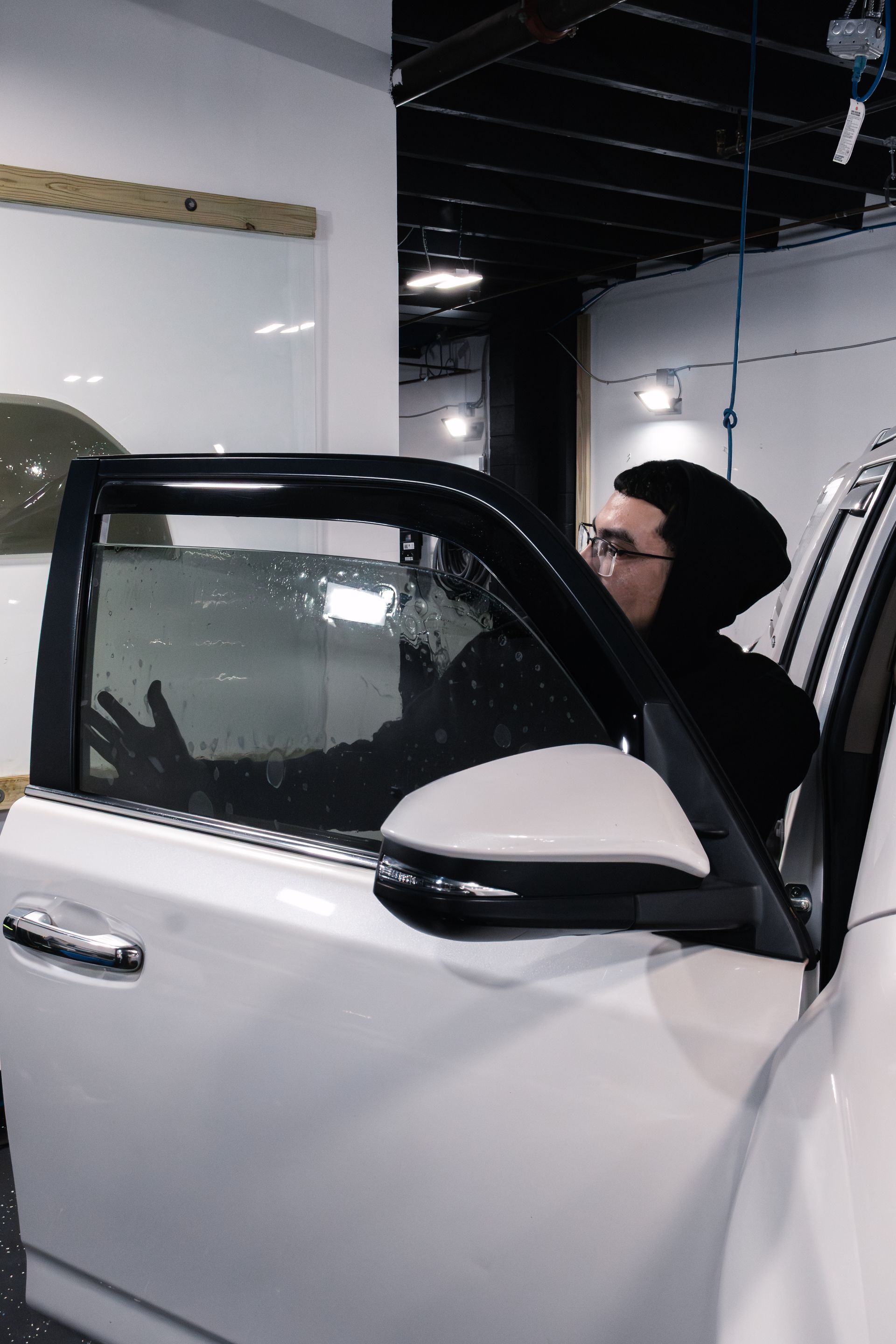 Blue car parked near a garage with white door.