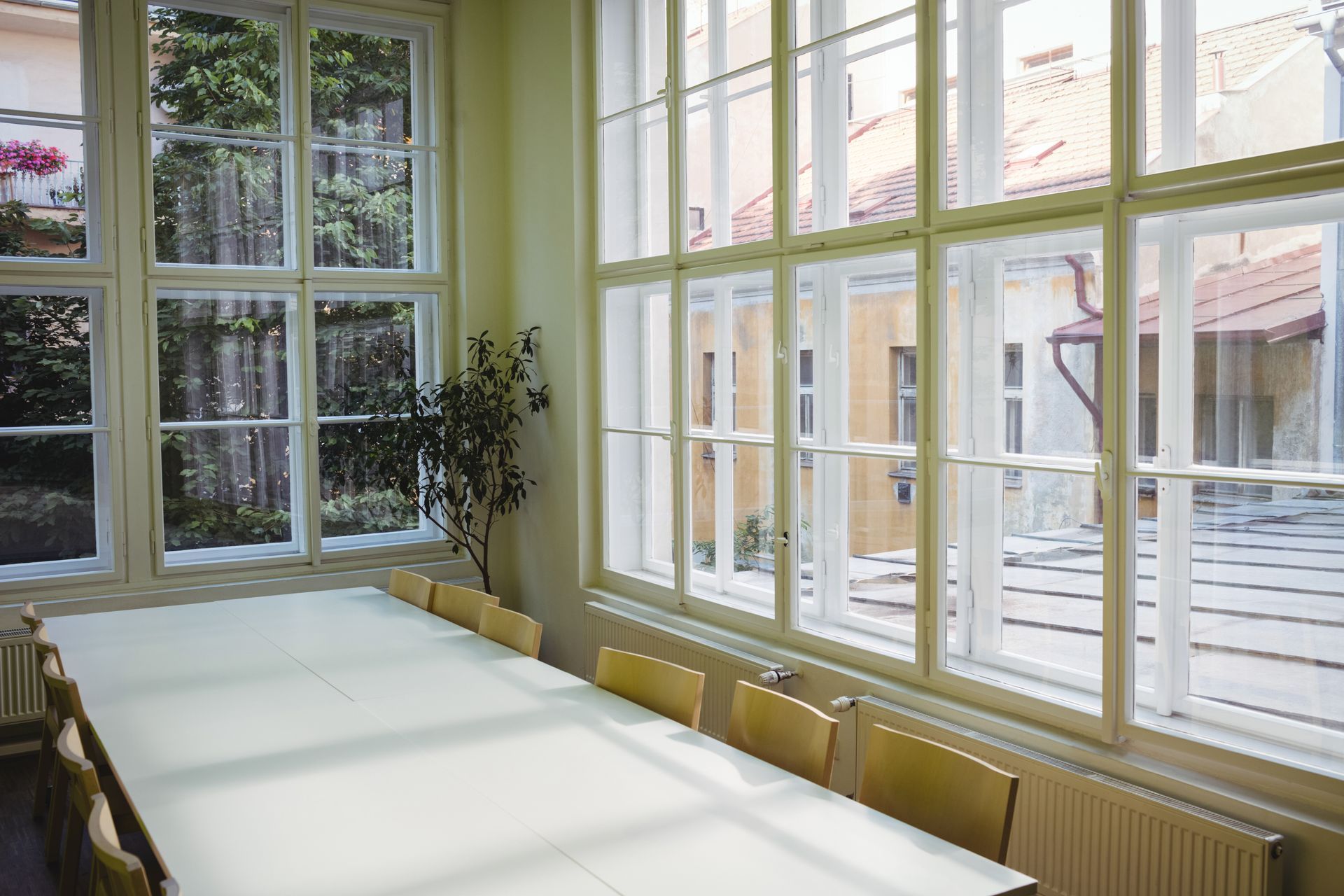 Long table in a light-filled room with large windows overlooking an outdoor courtyard.