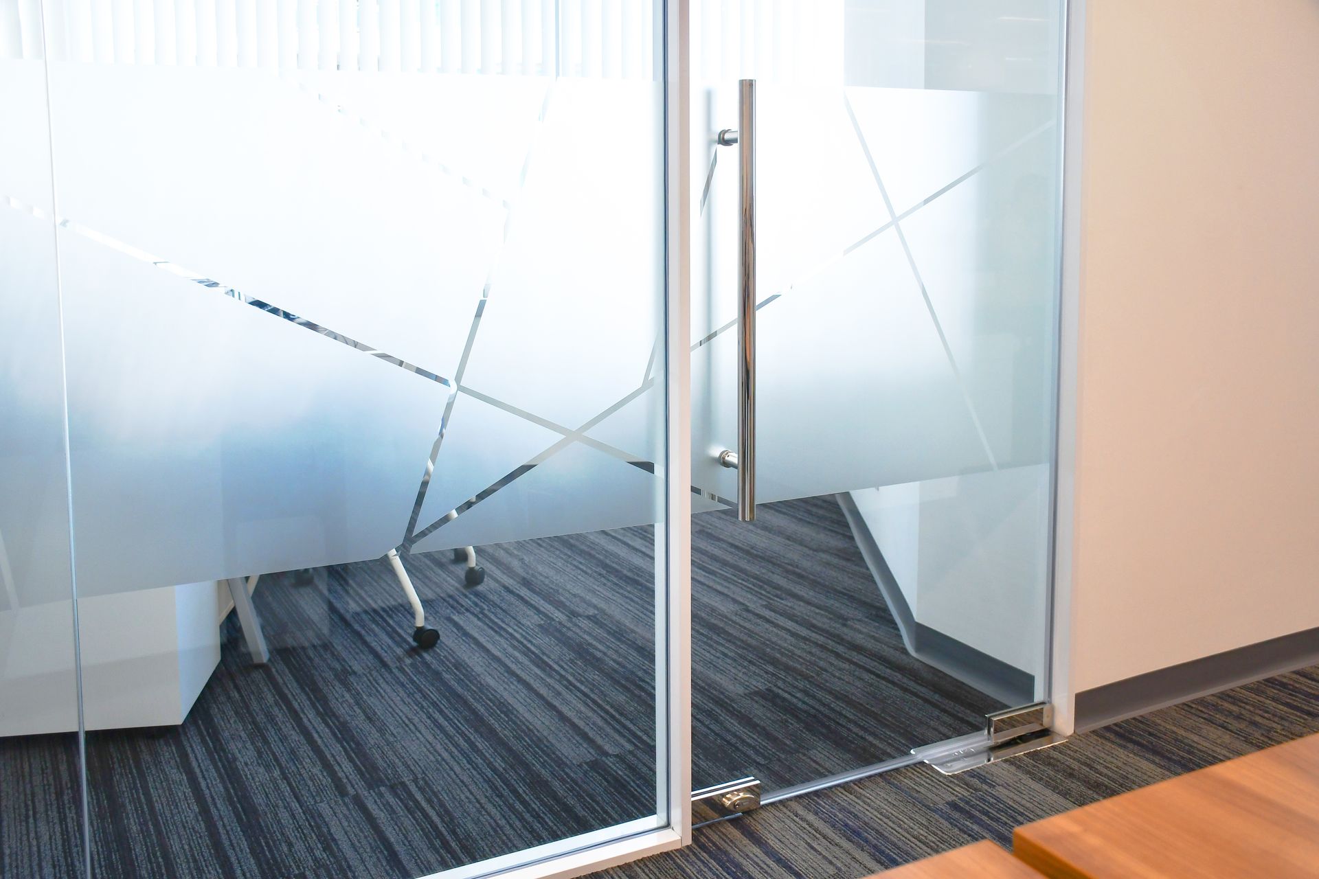 Glass office door with frosted geometric pattern; carpeted floor.