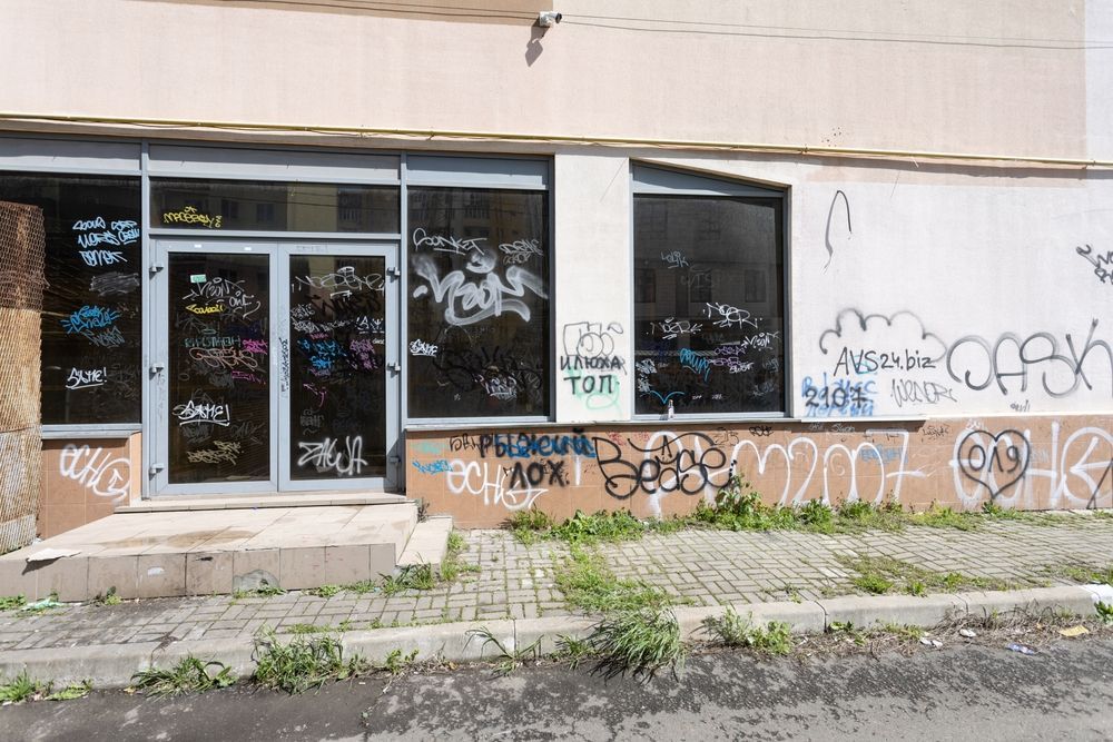 A storefront with graffiti-covered windows and door. Exterior appears run down.