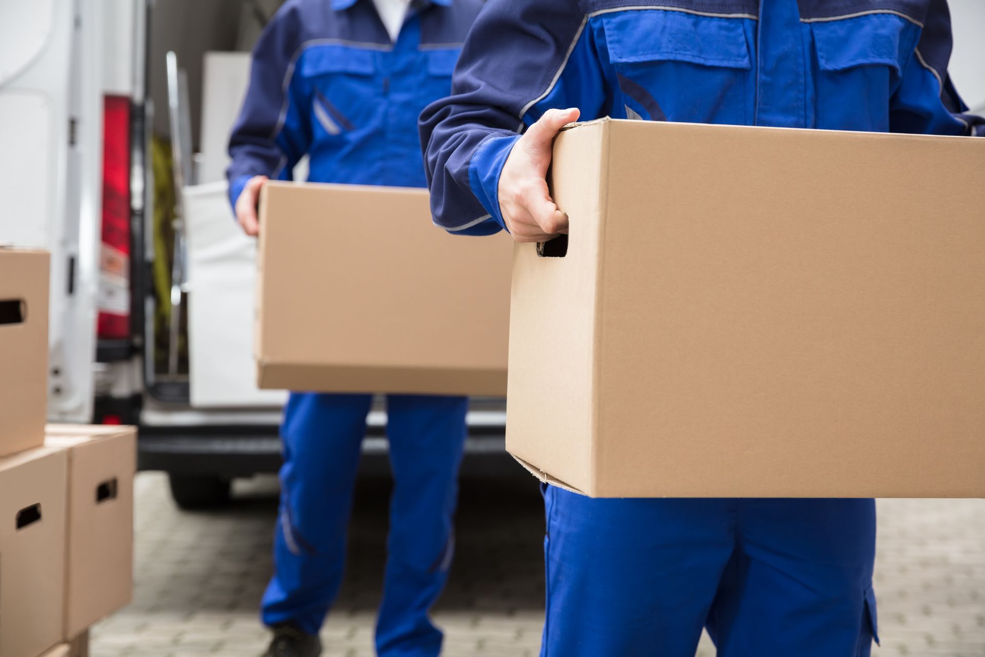 Workers carrying cardboard boxes from a moving van.