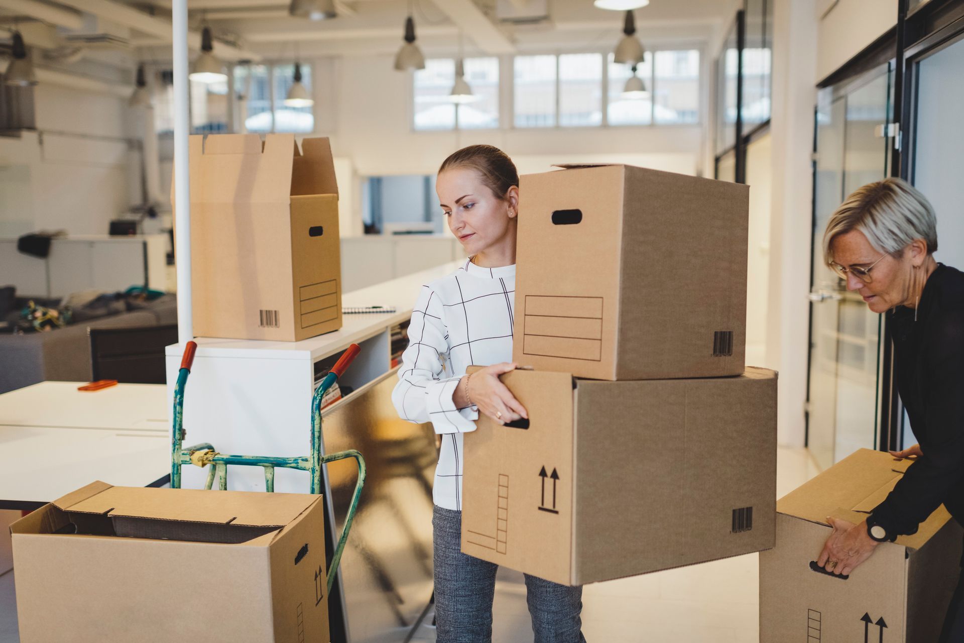 Women are moving boxes into a new office.