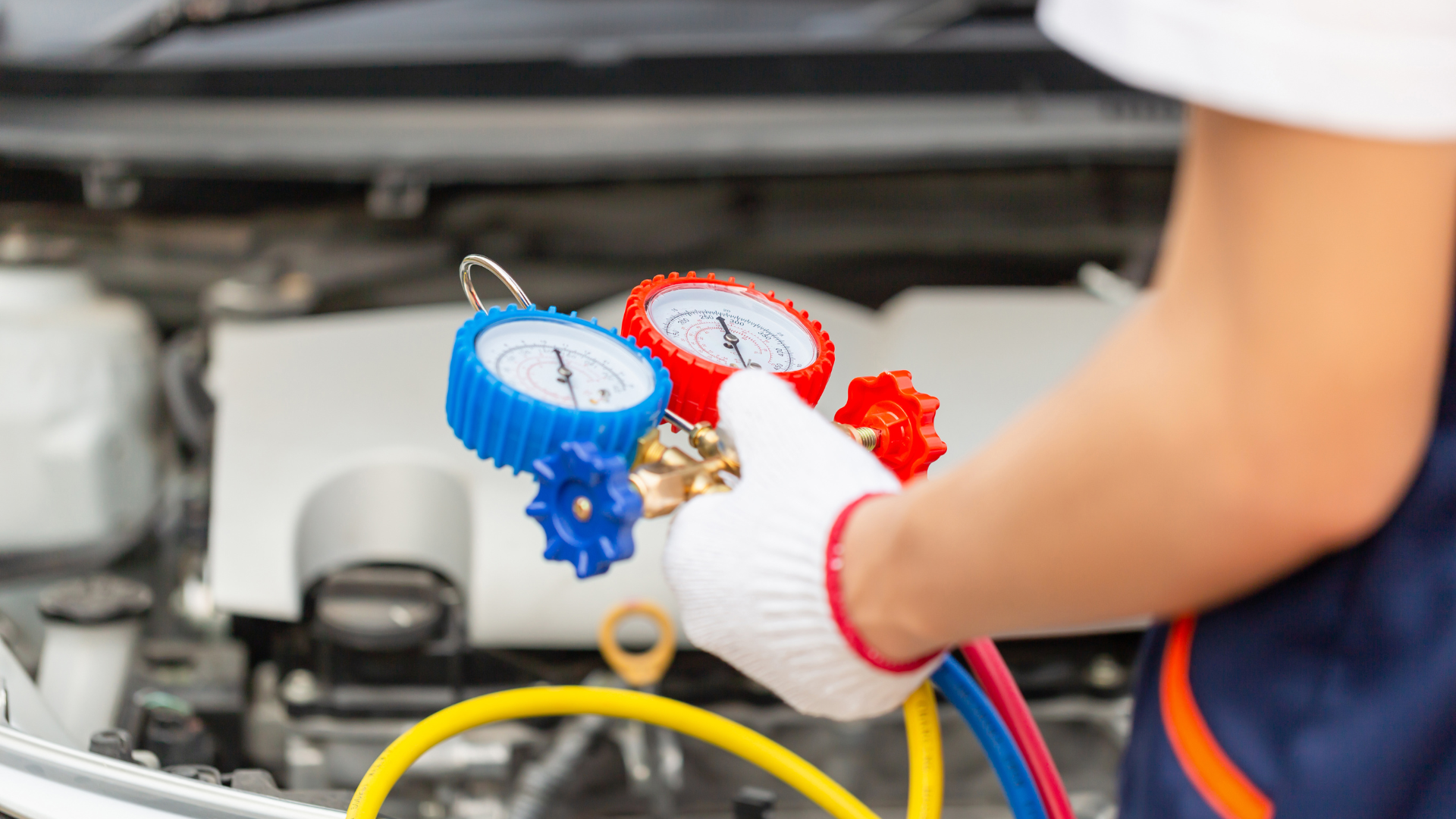 A person is holding a pair of gauges in front of a car.
