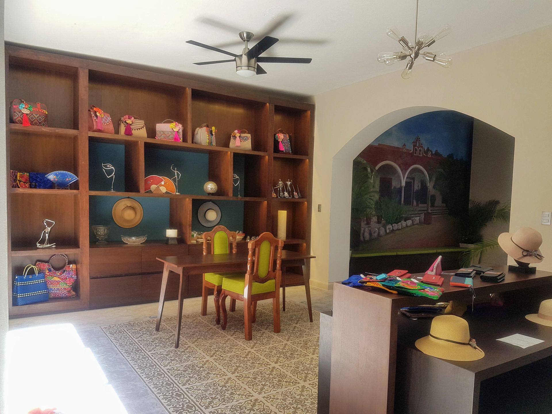 Una habitación con una mesa, sillas, estantes y un ventilador de techo.