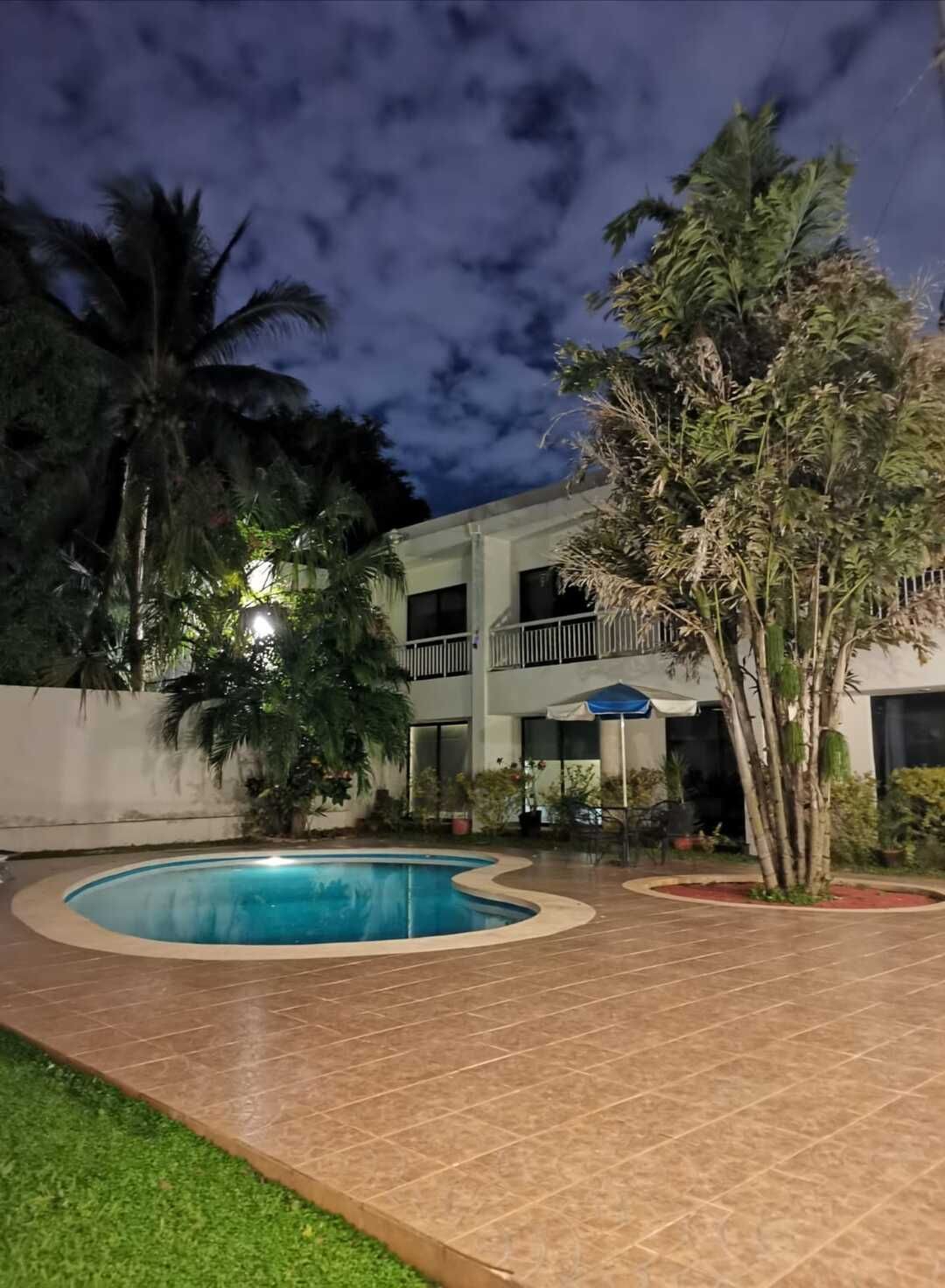 Una casa grande con piscina frente a ella por la noche.