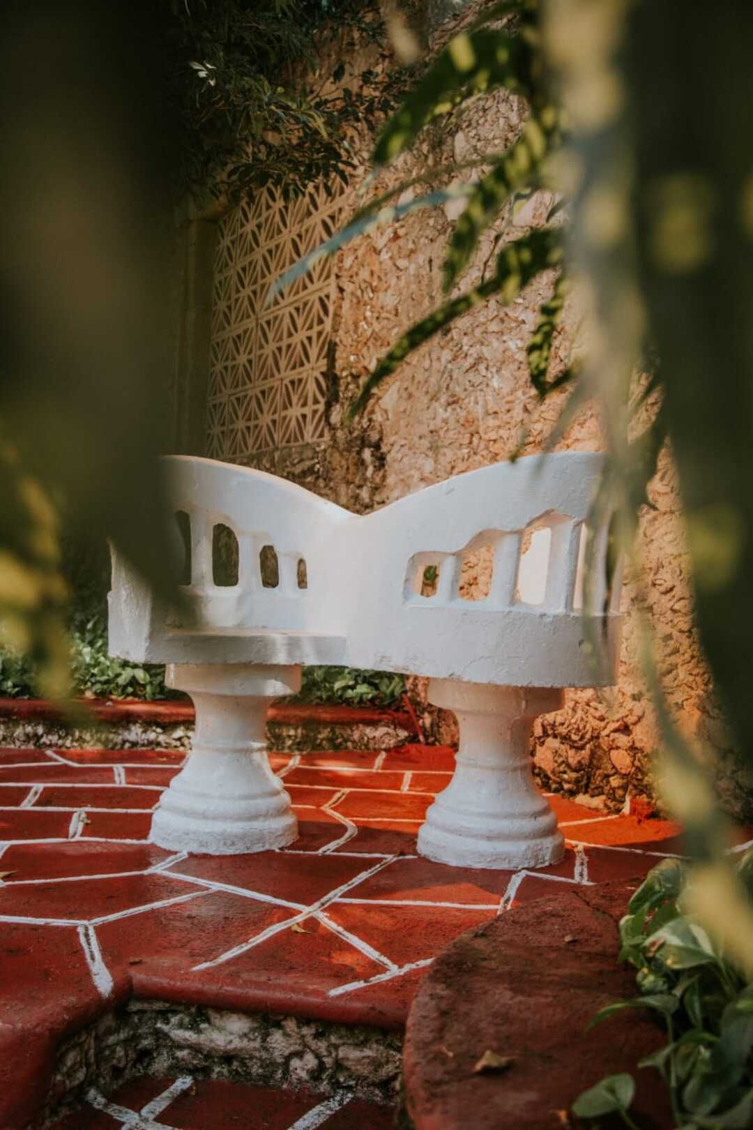 Un banco blanco está sentado sobre una pasarela de ladrillos.