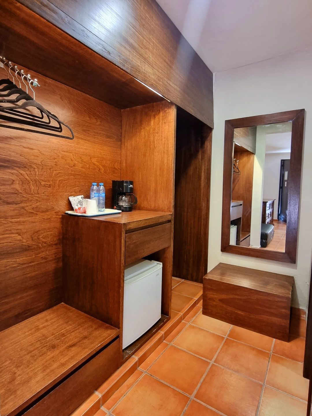 Una habitación de hotel con nevera y espejo.