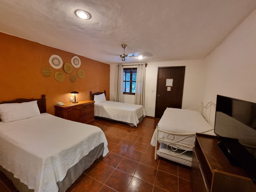 Una habitación de hotel con dos camas y un televisor de pantalla plana.