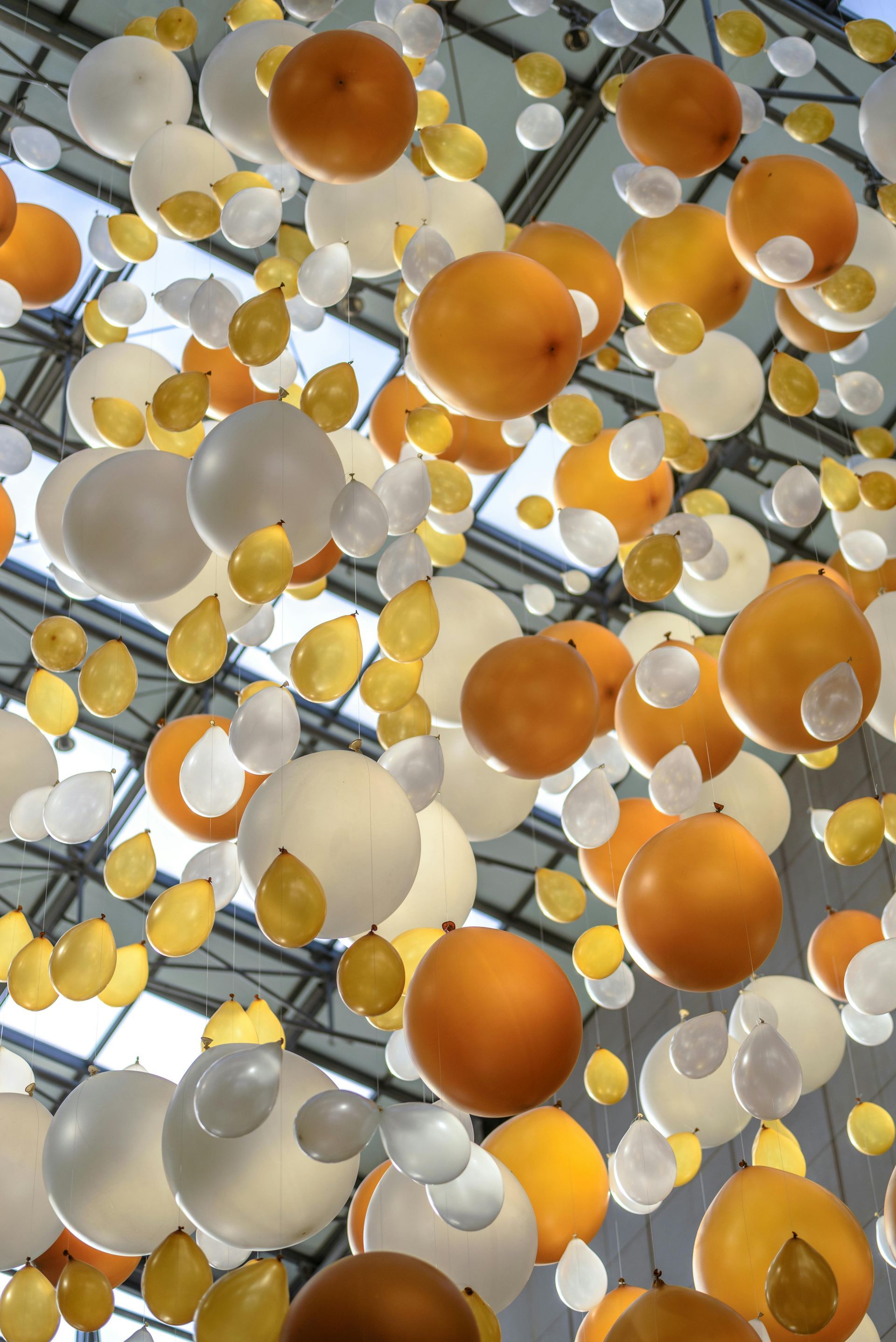 A bunch of orange and white balloons hanging from the ceiling