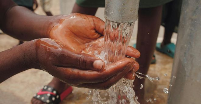 A person is washing their hands under a faucet.