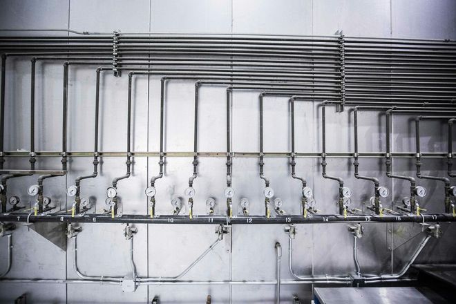A row of stainless steel pipes hanging on a wall.