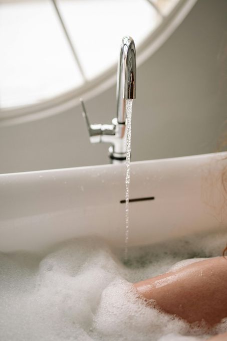 A woman is taking a bath in a bathtub filled with foam.