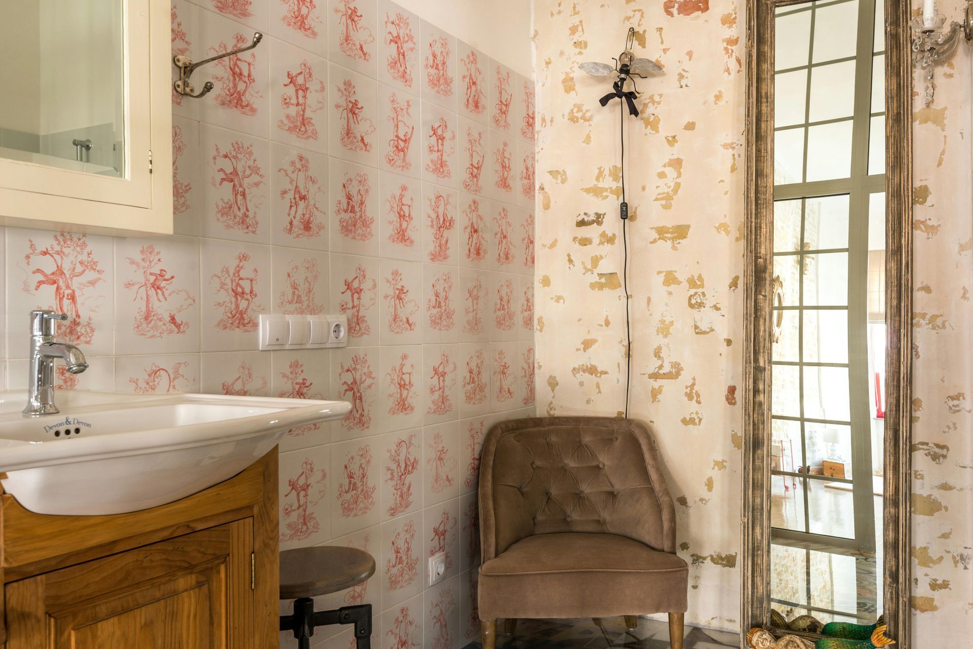 A bathroom with a sink , chair and mirror.