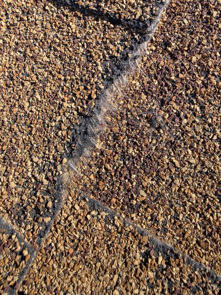 Close-up of brown asphalt shingles with visible cracks and granular texture.