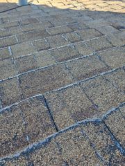Close-up of a shingled roof with a light coating of frost or snow.