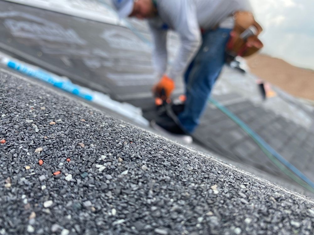 Woman in straw hat smiles, holding wine glass near a lake.