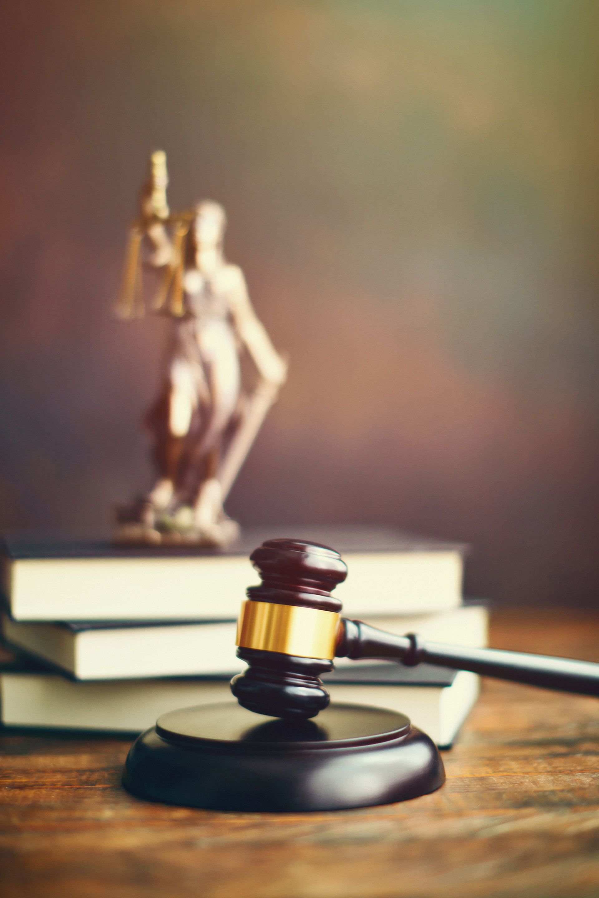 A judge 's gavel is sitting on a wooden table next to a statue of justice.