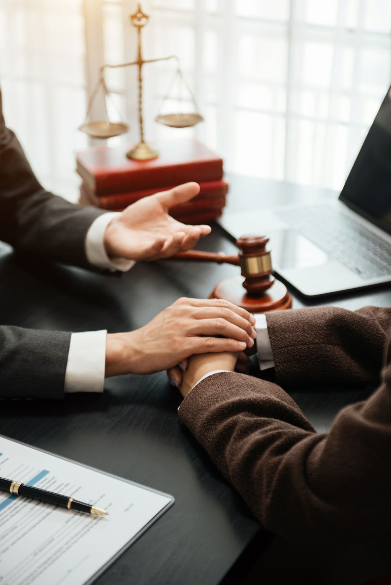 Two people are sitting at a table with a gavel and scales of justice in the background.