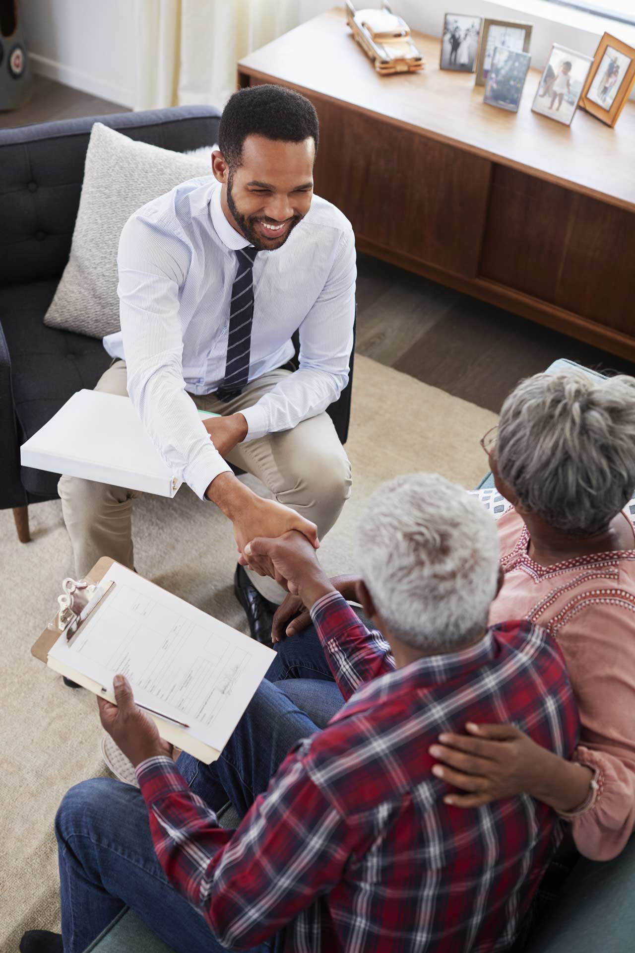 A man is sitting on a couch talking to an elderly couple.