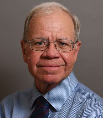 Man with glasses wearing a blue striped shirt and tie, looking at the camera.