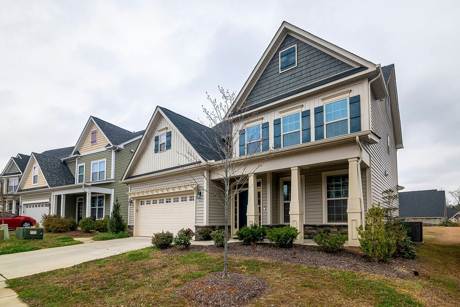 Row of suburban houses with beige and green siding under a cloudy sky.