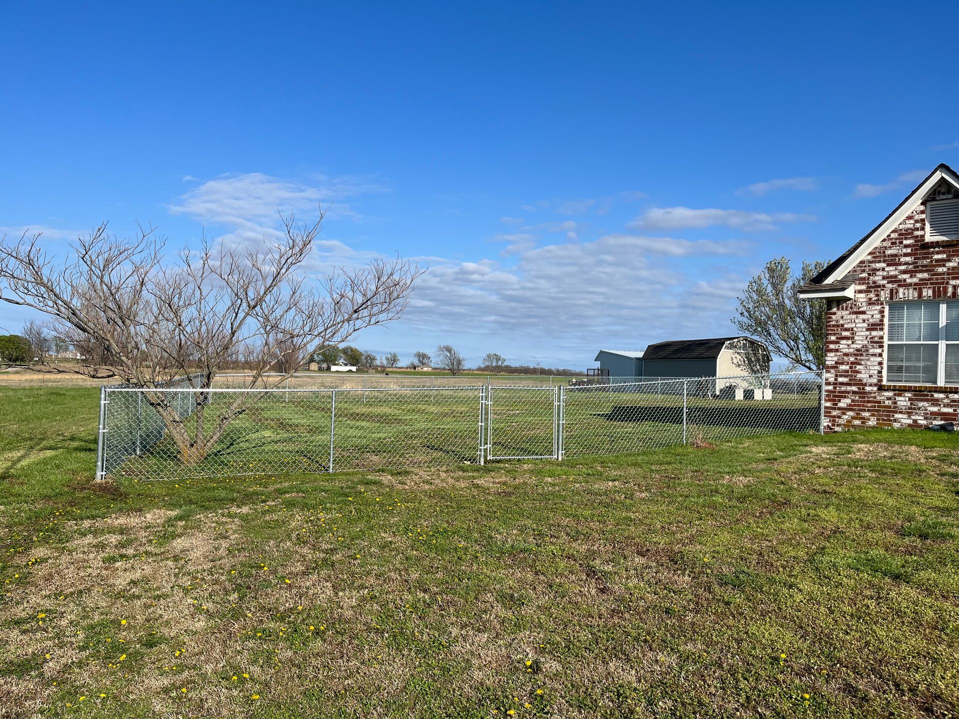 A brick house is sitting in the middle of a grassy field.