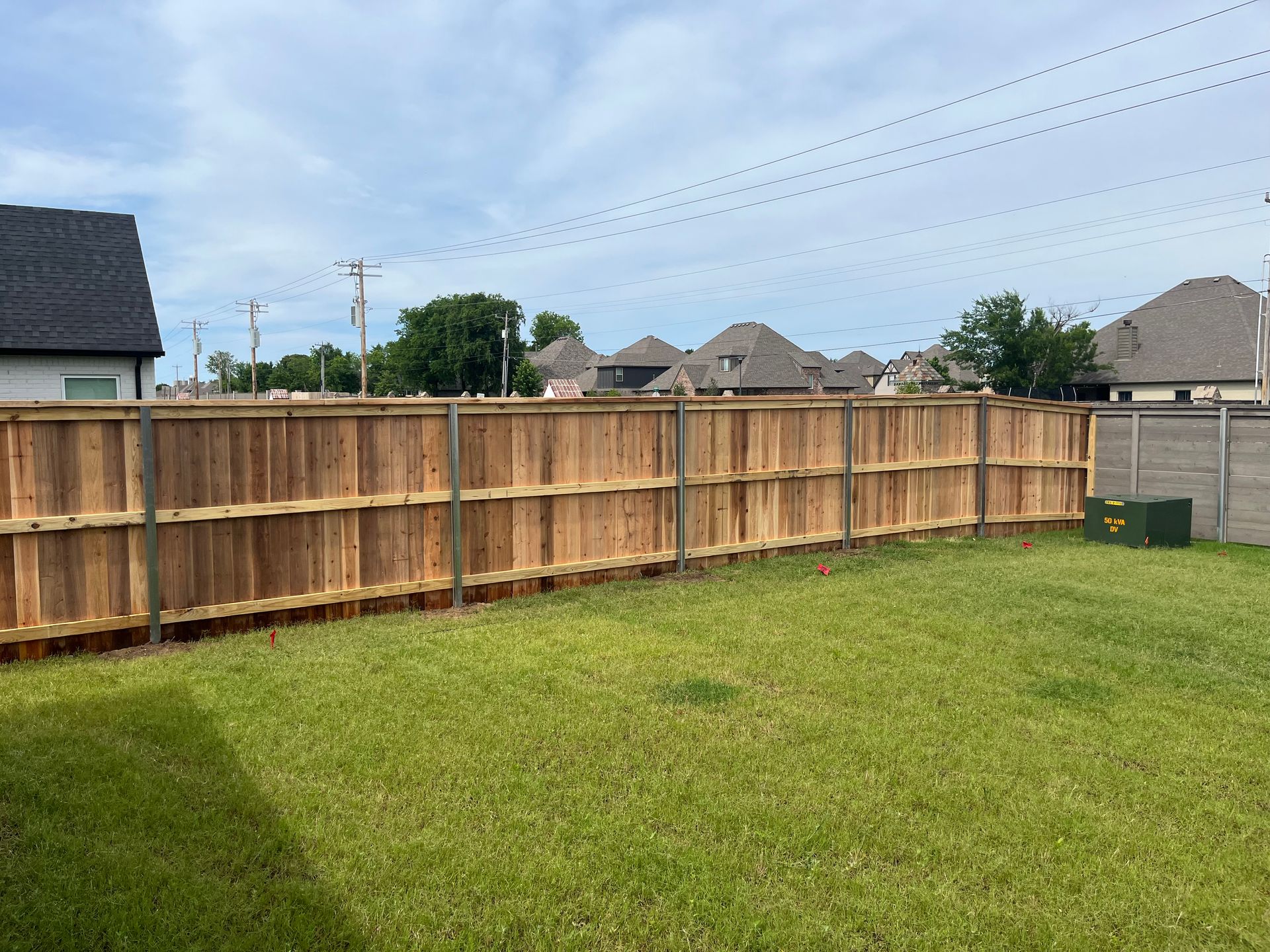 A wooden fence surrounds a lush green yard.