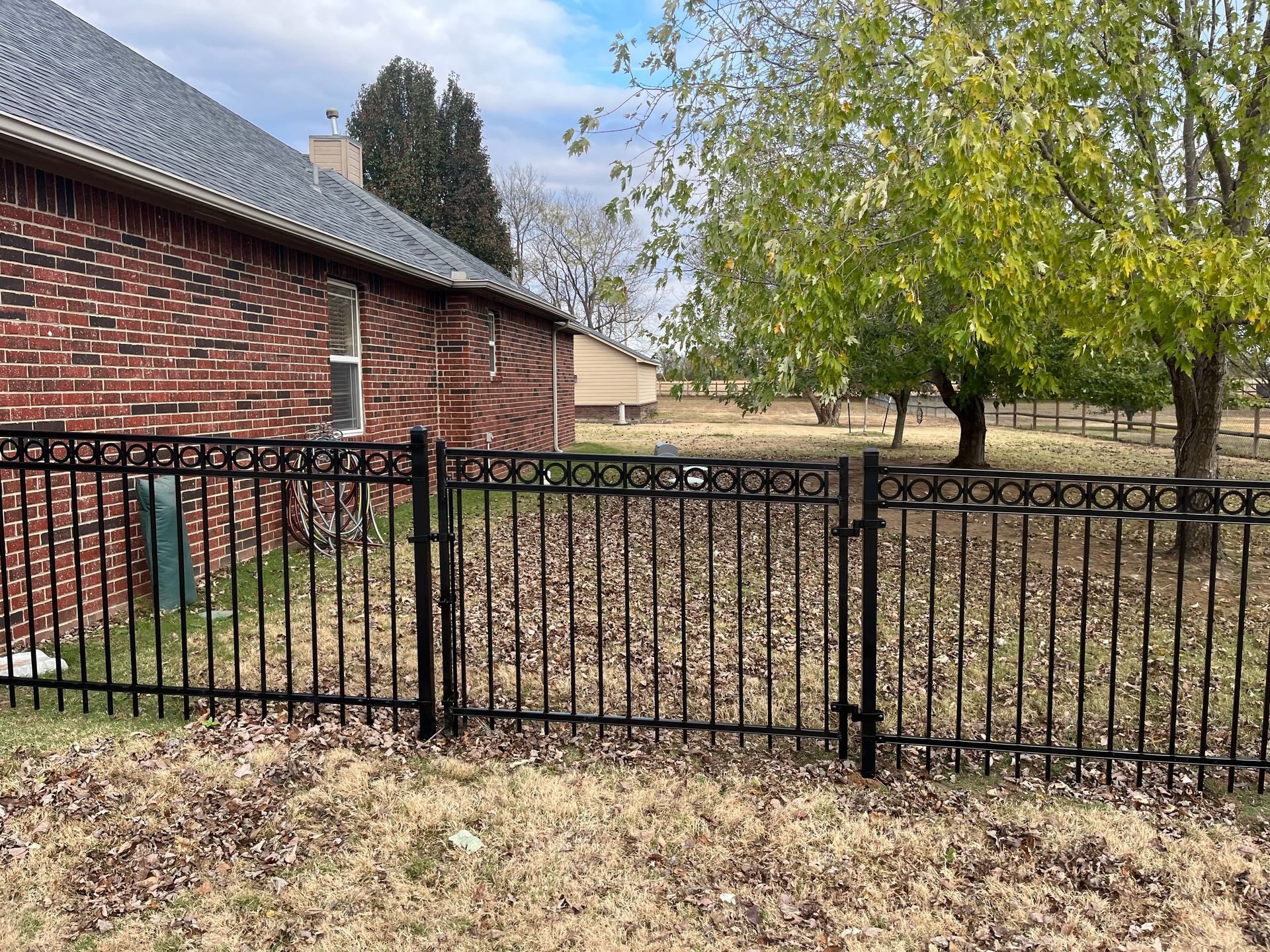 A black fence is in front of a brick house.