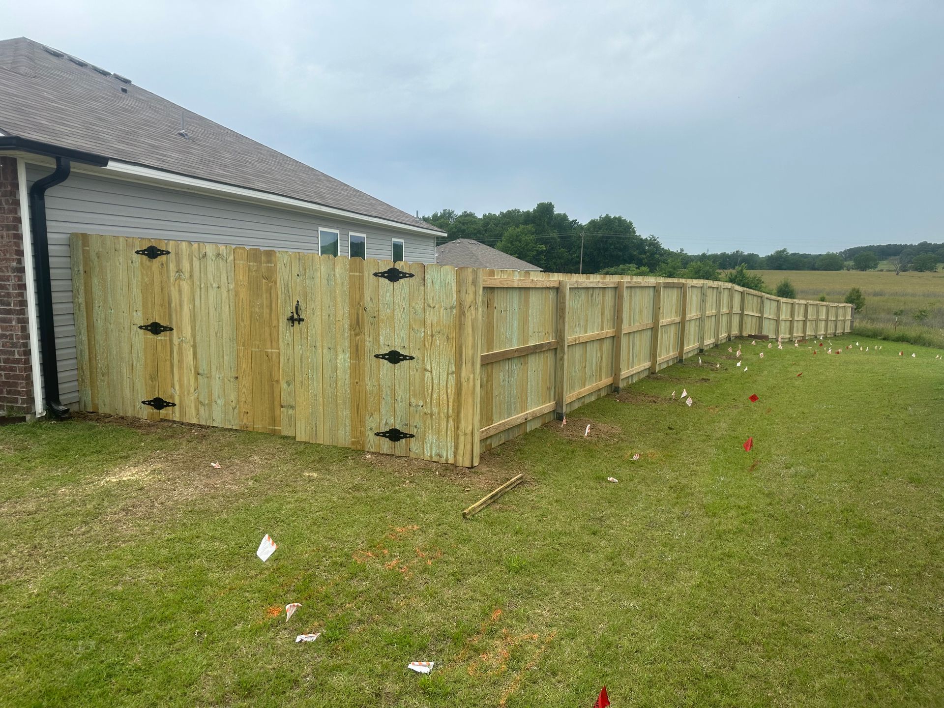 A wooden fence is sitting in the grass in front of a house.