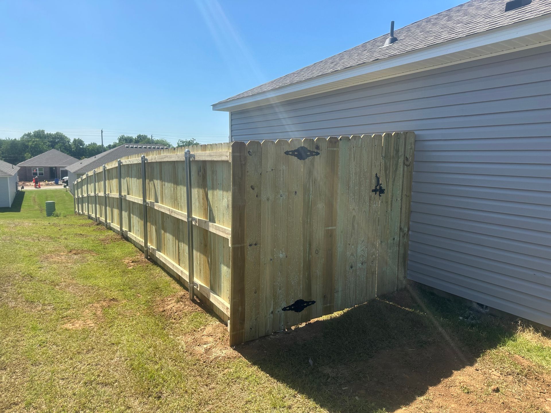 A wooden fence is sitting in the grass next to a house.