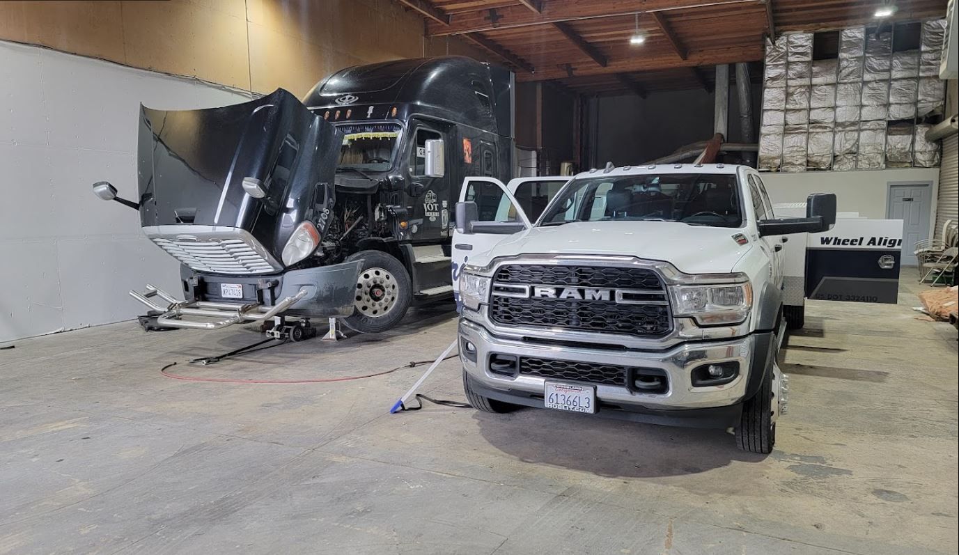 A ram truck is parked next to a semi truck in a garage.