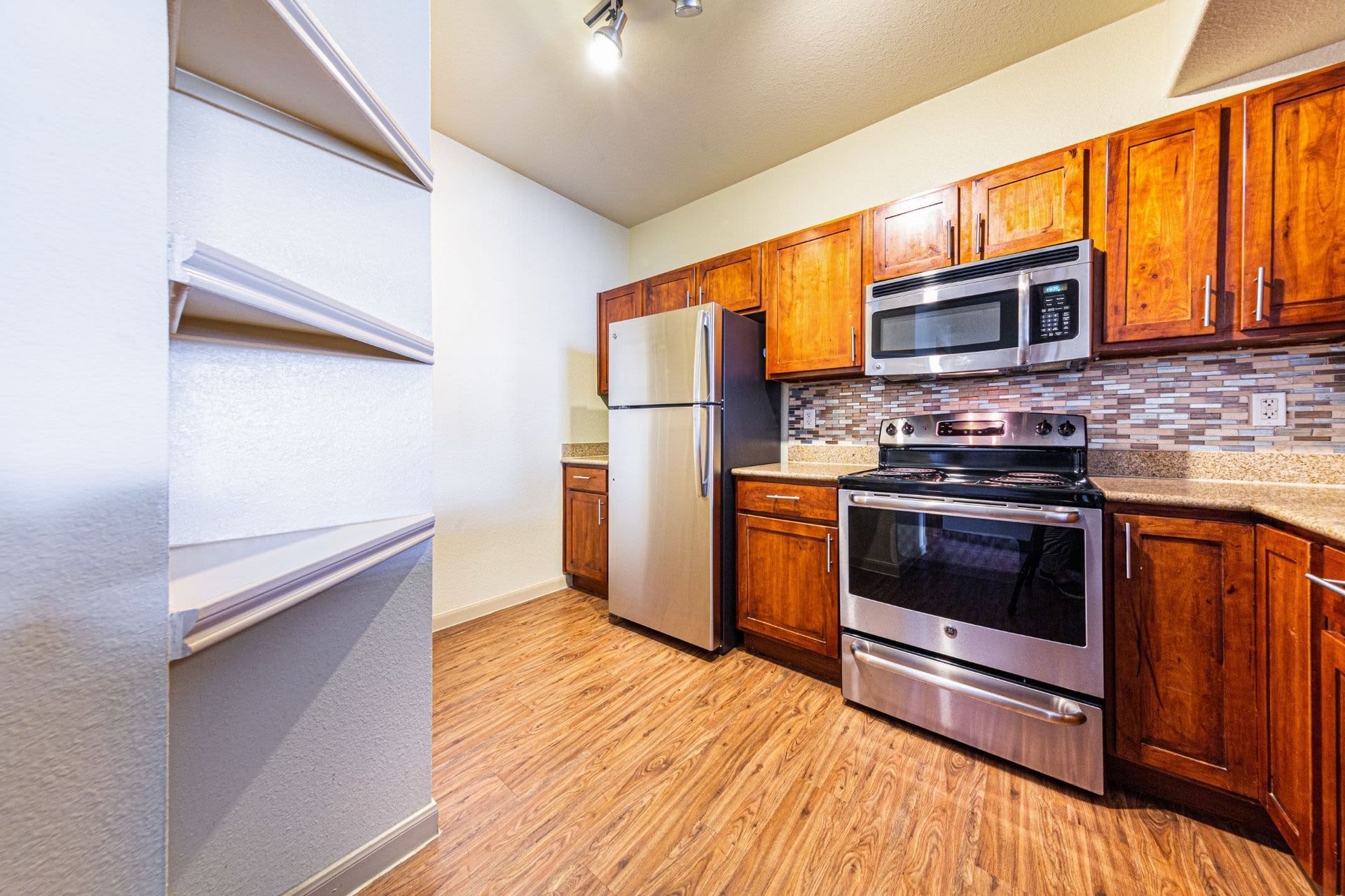A kitchen with stainless steel appliances and wooden cabinets at Marquis Grand Lakes in Richmond, TX.