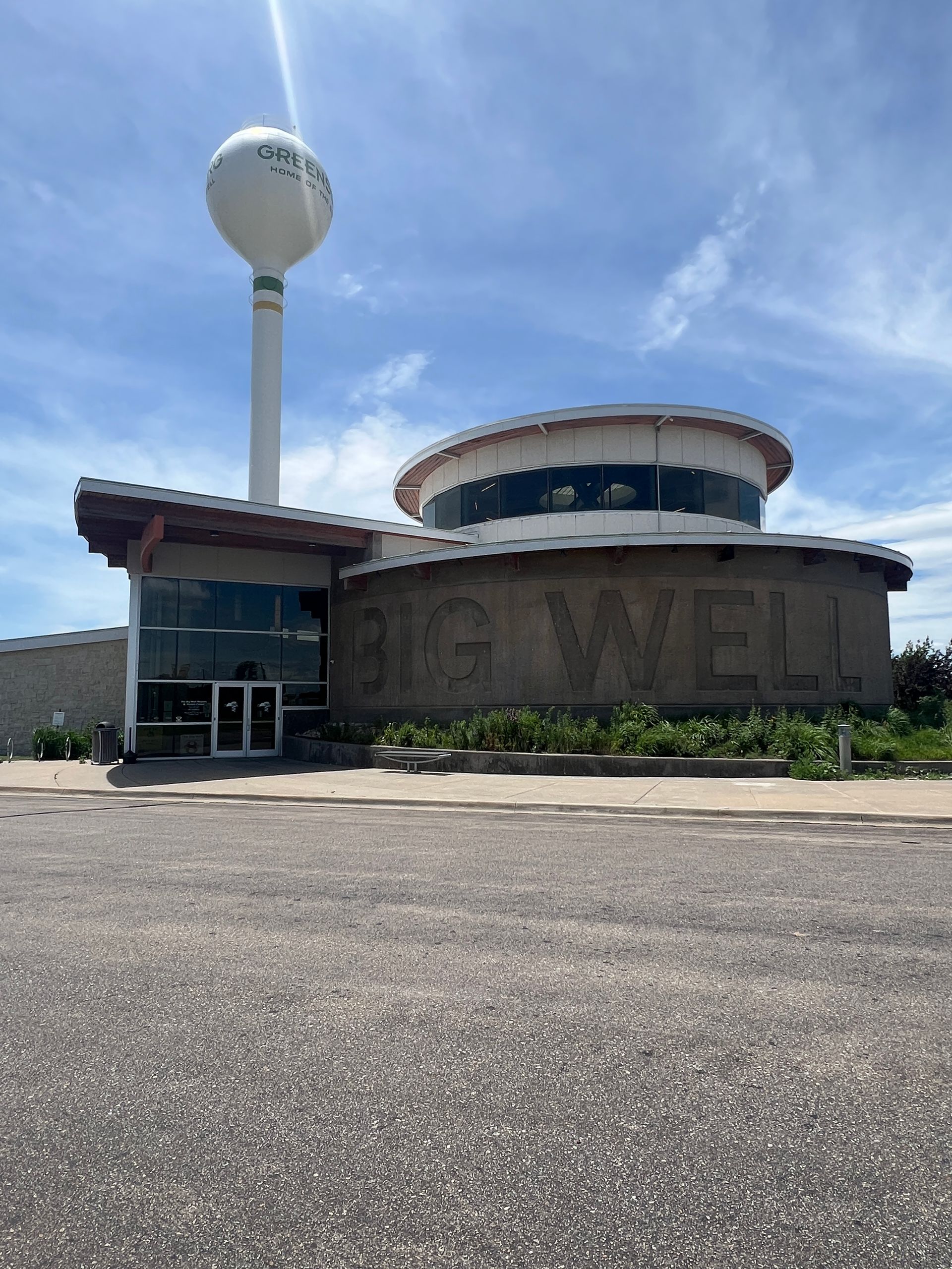 Round building with large “MARVEL” sign and water tower under a bright blue sky.