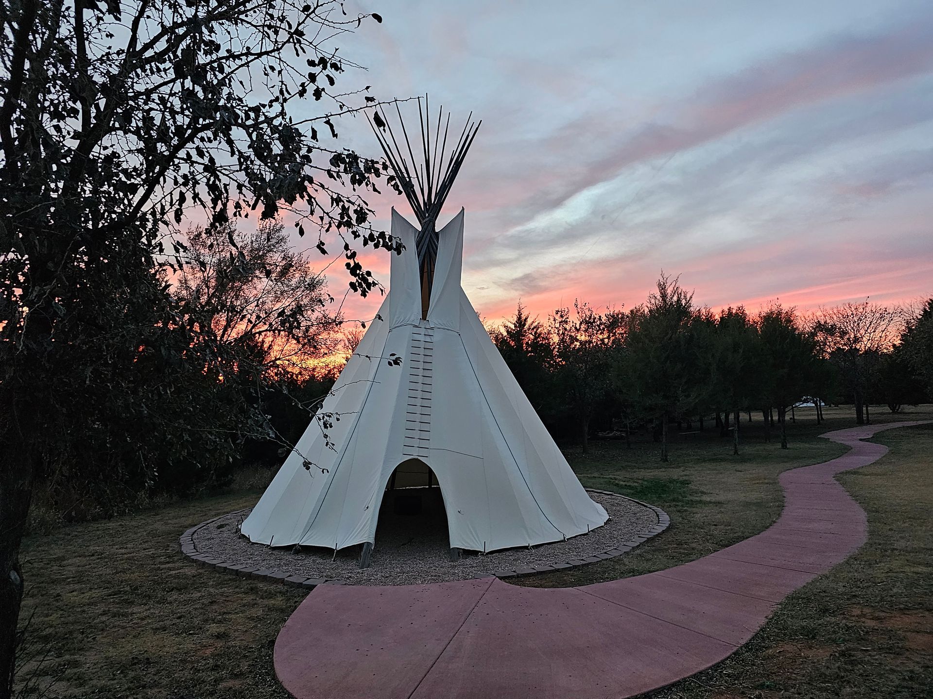 White teepee on a winding pink path at sunset in a park