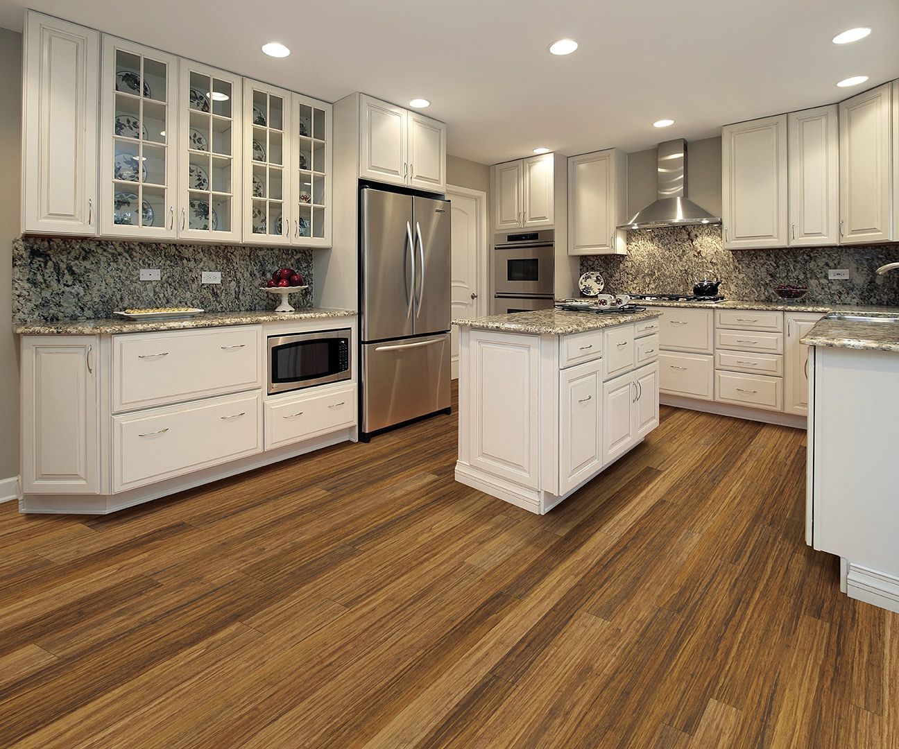 Kitchen with white cabinets, stainless steel appliances, granite countertops, and wood flooring.